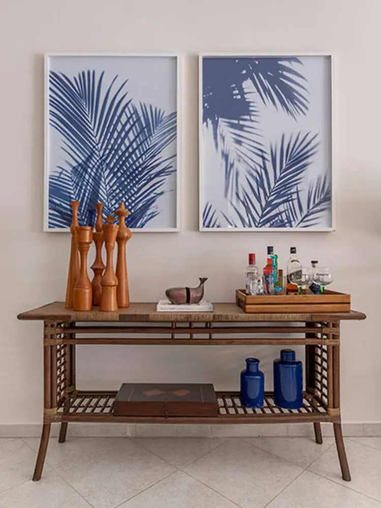 Cantinho do bar com bebidas, itens decorativos, móvel de madeira e quadros azuis. 