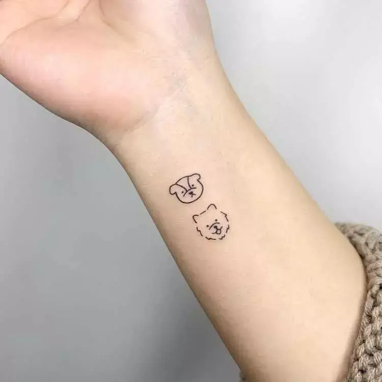 tatuagem de contorno de rosto de dois cachorros no pulso na parte inferior, mas lateral