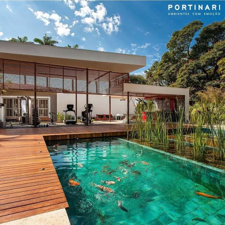 Piscina biológica no quintal de uma enorme casa, com uma academia e deck de madeira ao lado. 