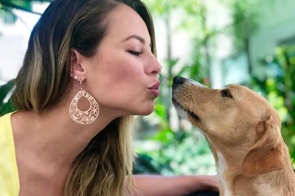Paolla Oliveira de roupa amarela quase beijando cachorrinho caramelo
