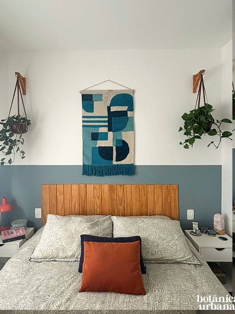 Quarto com cama de casal, cabeceira de madeira e pintura azul, flâmula azul, mesas de cabeceira e vasos suspensos 