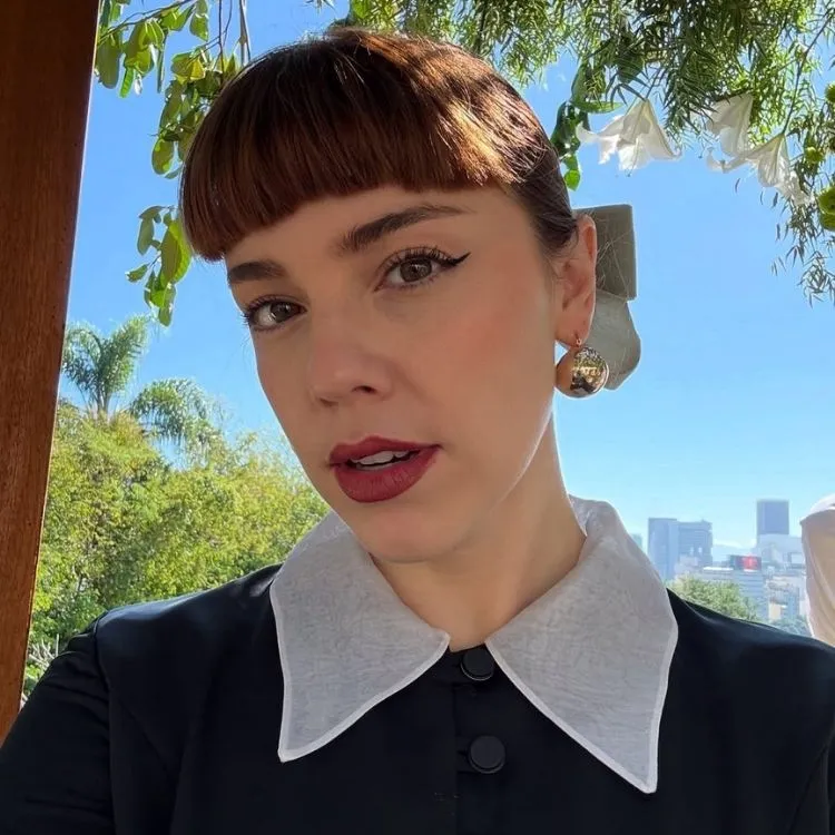 Foto de Alice Wegmann em cena usando um dos looks da Solange Duprat em Vale Tudo, batom vermelho e vestido preto com gola branca