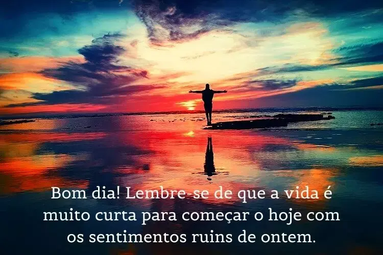 Foto de pessoa na praia com céu colorido e frase: Bom dia! Lembre-se de que a vida é muito curta para começar o hoje com os sentimentos ruins de ontem.