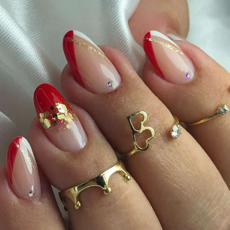 Unhas vermelhas decoradas com glitter escapsulado, risco dourado e pedrarias