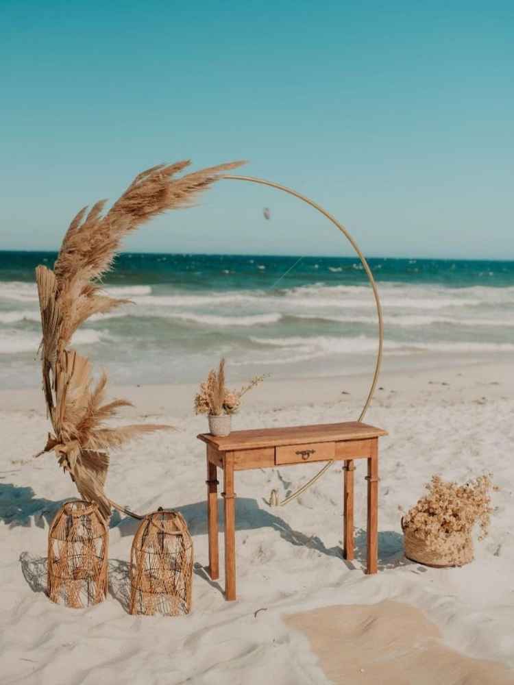 Decoração de casamento simples na praia com flores e folhas secas.