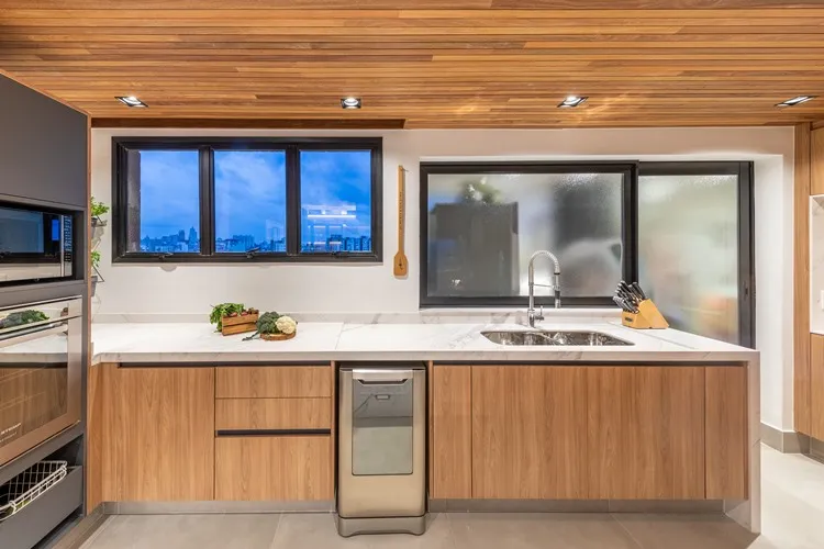 Cozinha de apê de 187 m² decorada pelo arquiteto Pietro Terlizzi, com bancada em mármore branco, pia inox, lava-louças embutida, janelas