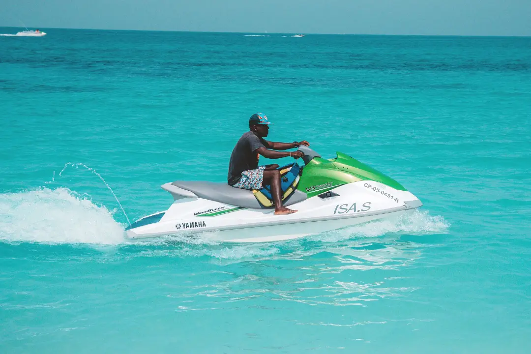Imagem de um homem em cima de um Jet Ski branco e verde em uma praia paradisíaca Imagem de um homem em cima de um Jet Ski branco e verde em uma praia paradisíaca.