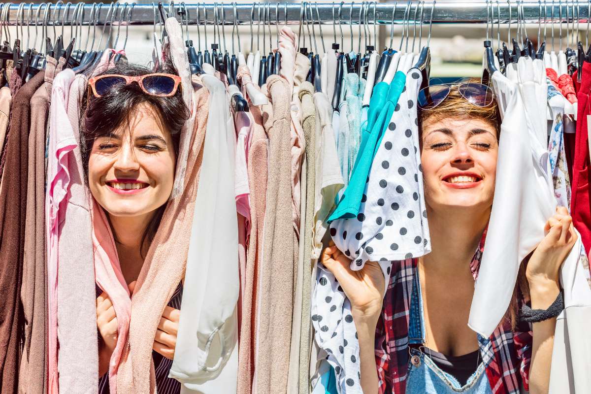 Duas mulheres em meio a roupas em arara