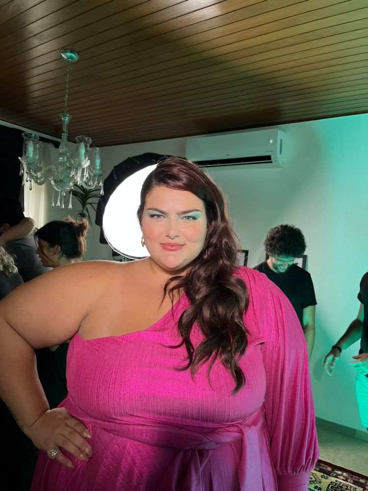 Mayara Russi com vestido rosa, manga comprida apenas de um lado. Cabelo com penteado jogado para lado direito. Sombra verde nos olhos