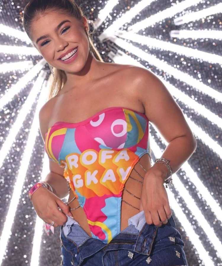 Mulher de pele clara usando abadá da farofa da Gkay como body sem alça com detalhes em corrente e shorts jeans