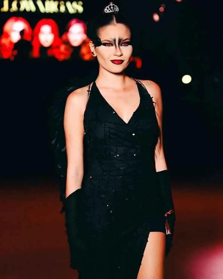 Mulher de pele clara com maquiagem e fantasia de cisne negro