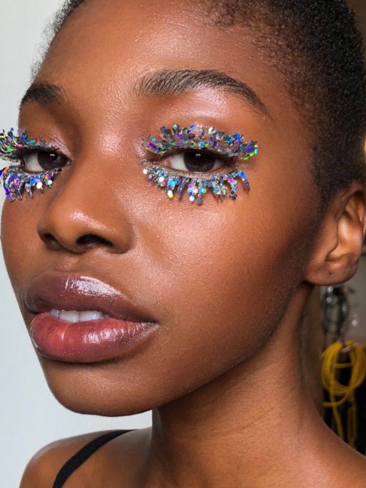 Mulher de pele negra com cílios postiços com glitter flocado 