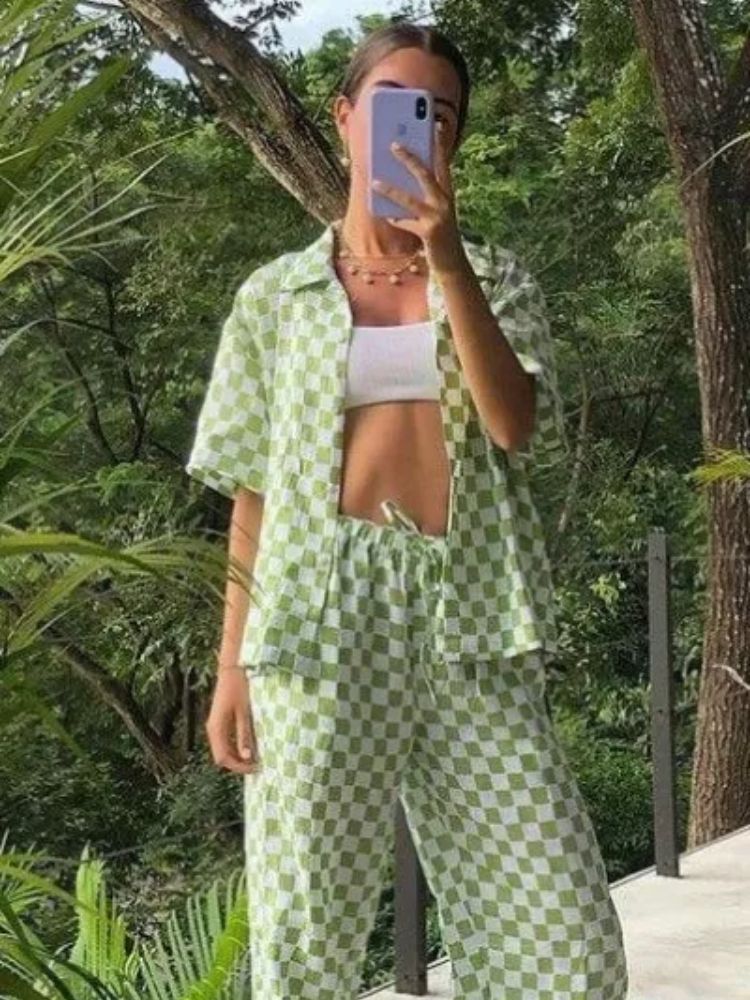 Mulher de pele clara usando top branco e camisa com calça xadrez de branco e verde
