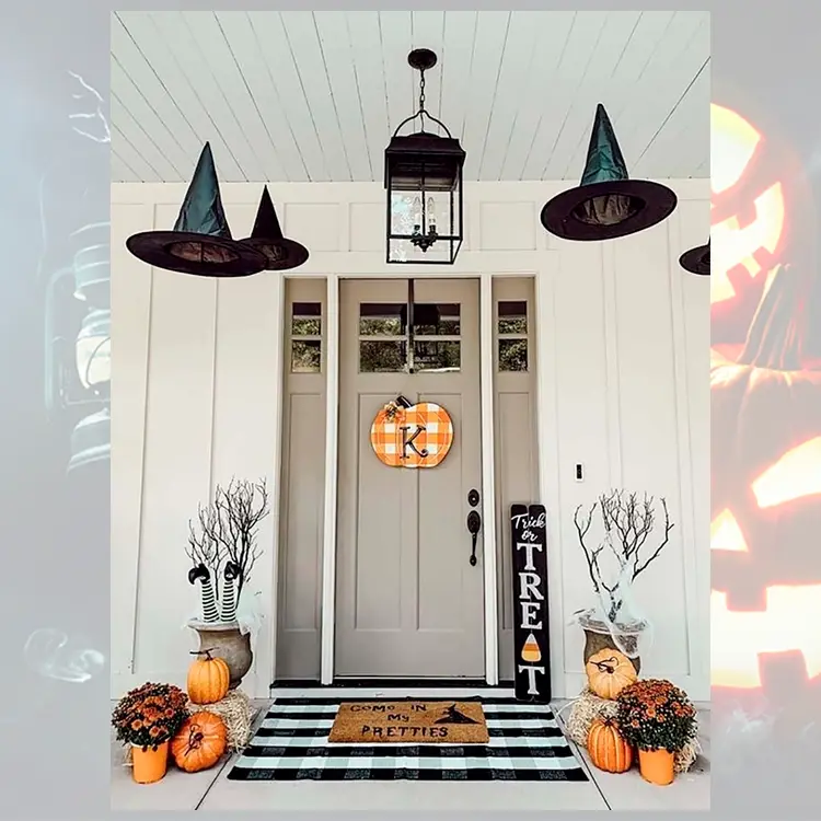 Foto de decoração de porta para o Halloween com chapéus de bruxa, abóboras, tapete escrito "come in my pretties", teias nos vasos, canelas de bruxa no vaso, placa escrito "trick or treat"