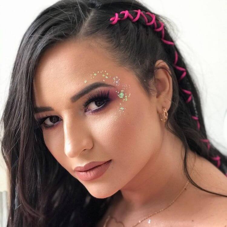 Mulher de pele clara usando maquiagem rosa discreta e glitter em volta dos olhos 
