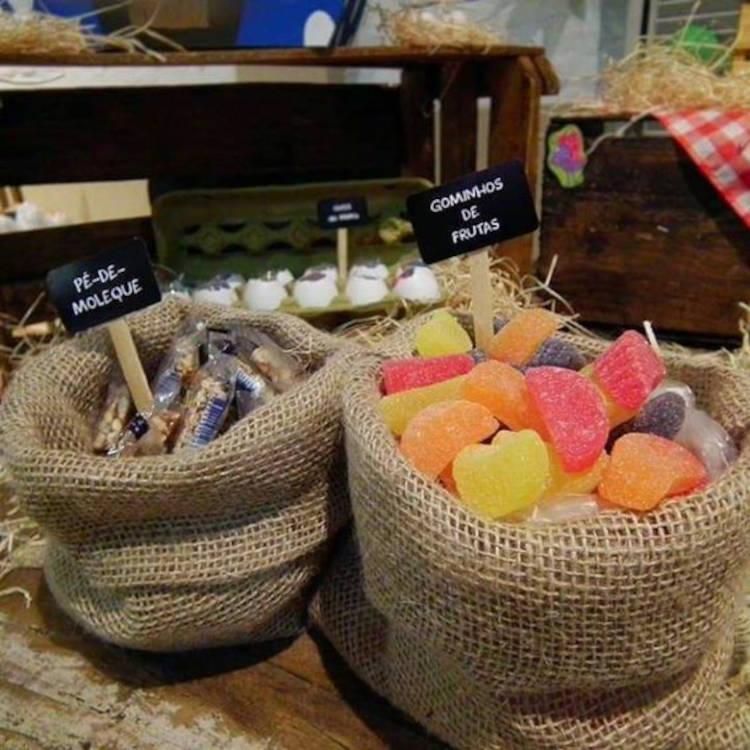 A imagem representa saco com doces e tags escrito pé-de-moleque e gominhos de frutas