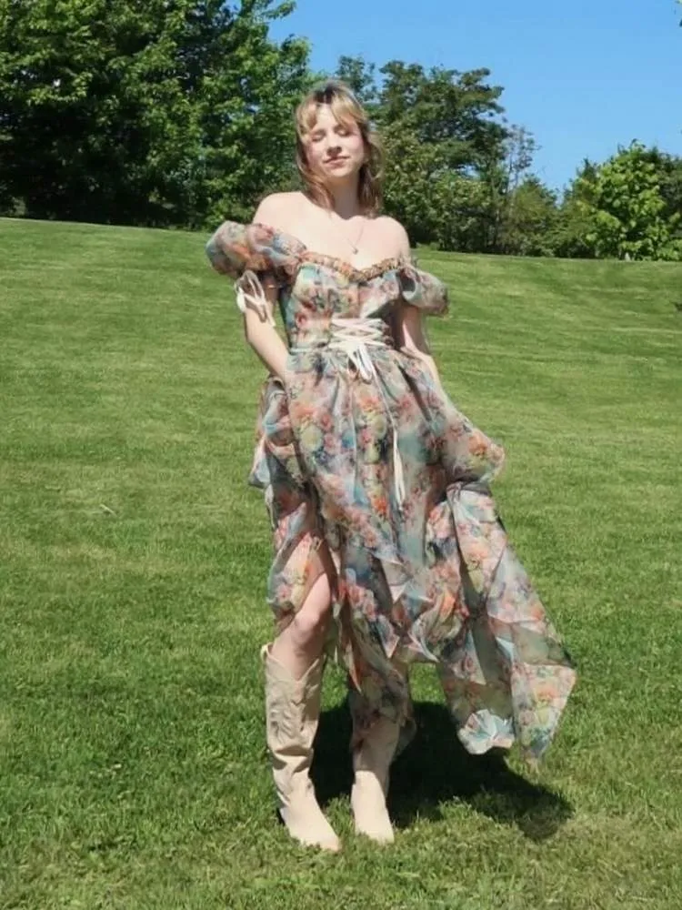 Mulher de pele clara com vestido floral esvoaçante e bota western
