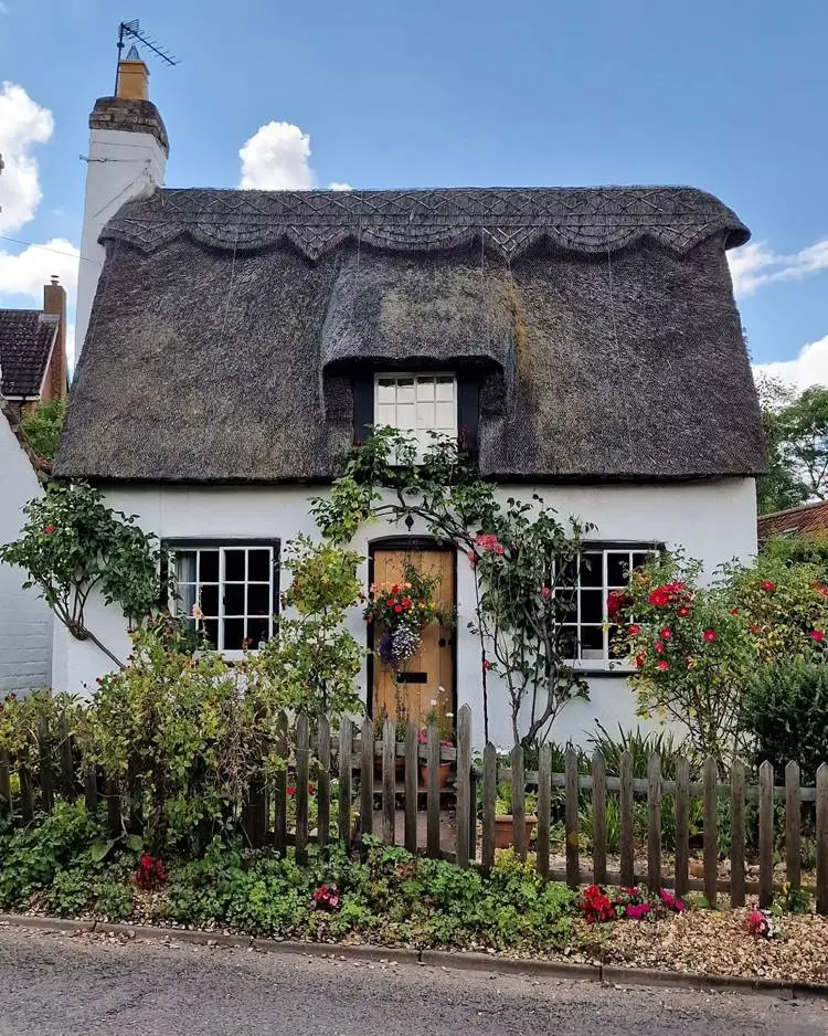 Casa de roça com conserto e várias flores e plantas decorando a entrada do jardim.