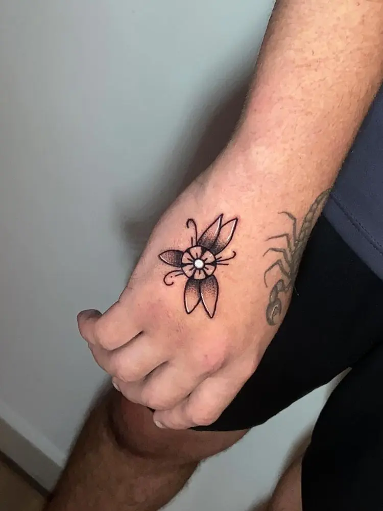 Mão masculina com flor old school e escorpião