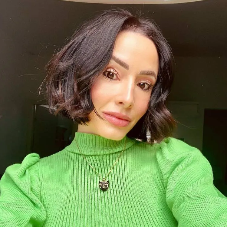 Mulher de pele clara com cabelo chanel messy e sueter verde
