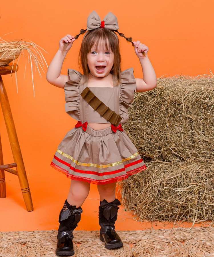 Garoto usando look junino com botas de cano longo pretas.
