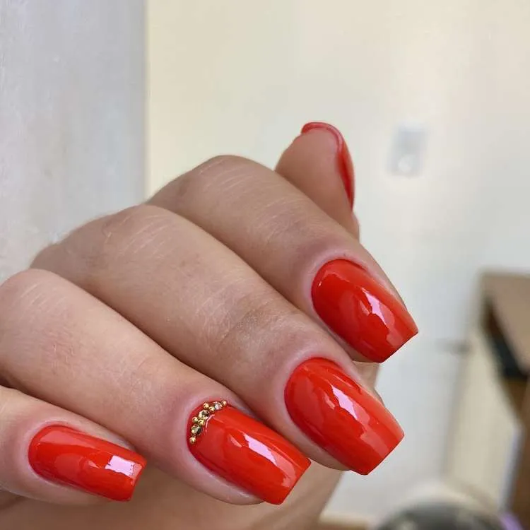 Unhas vermelhas decoradas, quadradas, com pedraria na filha única