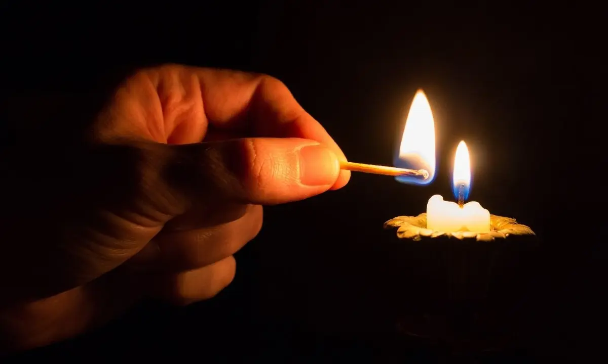 Imagem de homem acendendo uma vela.