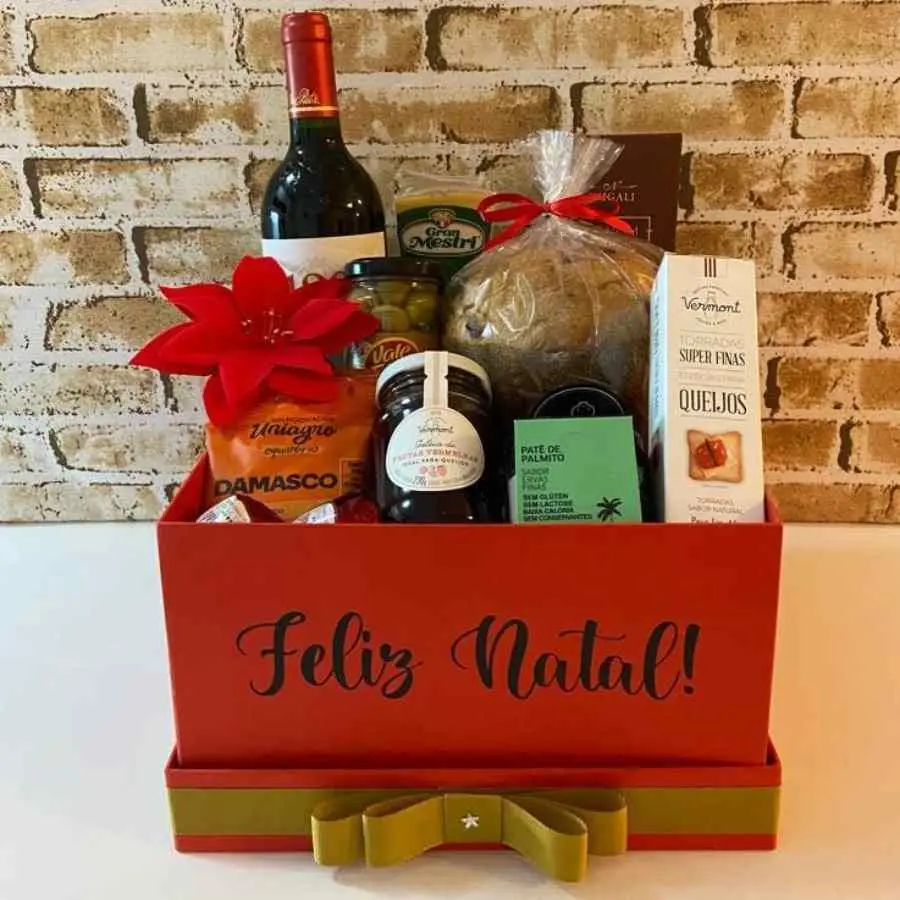 Foto de caixa de papel, com panetone, vinho, queijos e geleia. 