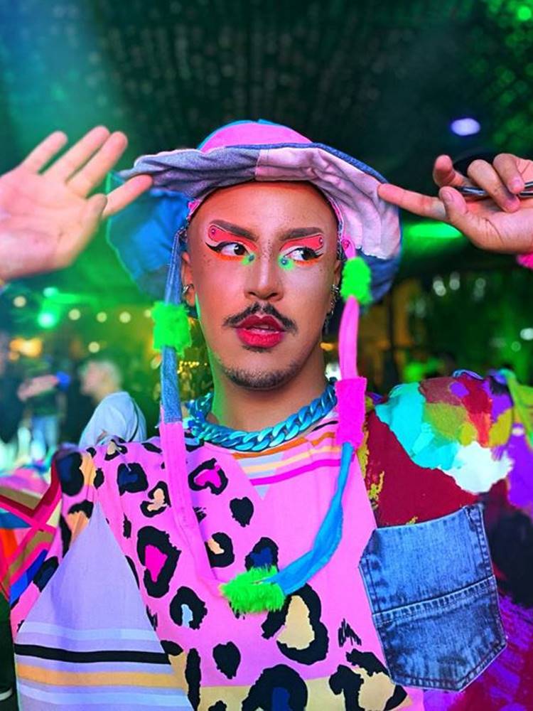Homem com look colorido + make gráfica nos olhos em cores neon