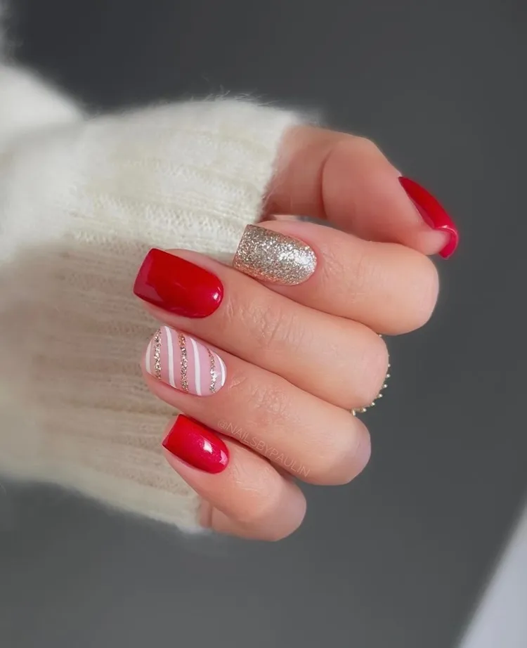 Mão com unhas decoradas para Natal em vermelho, dourado e branco
