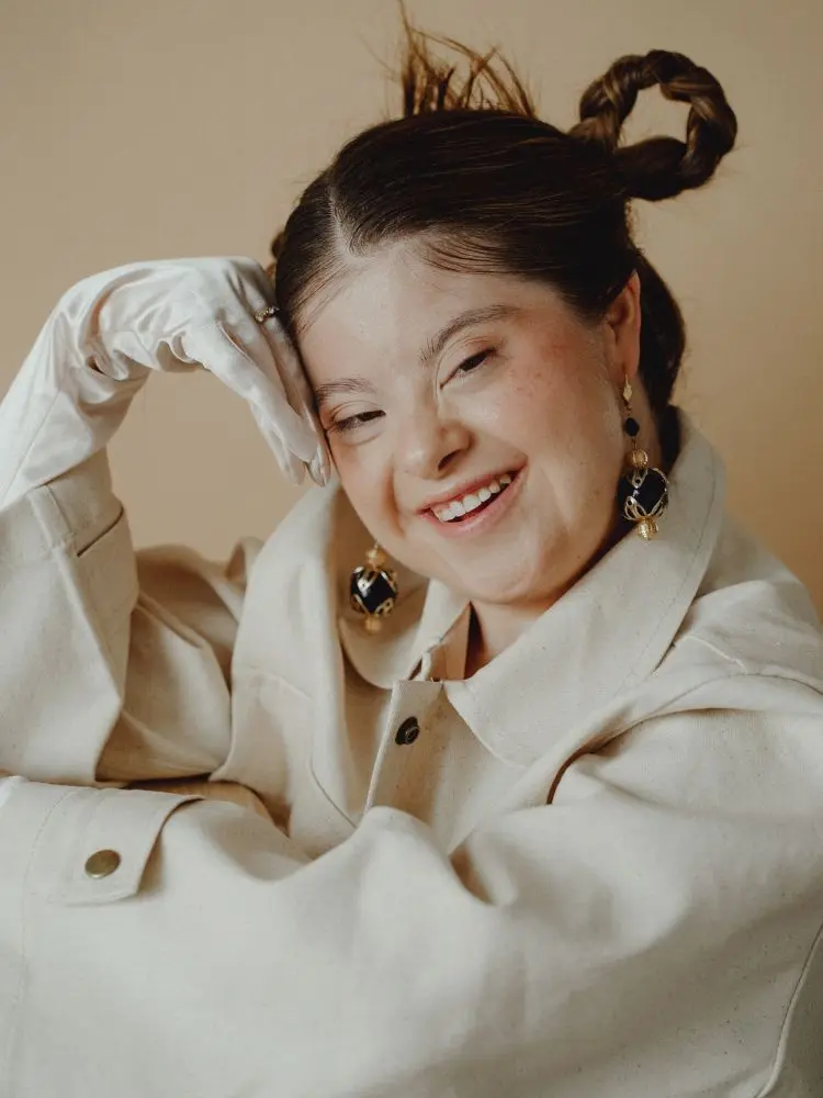 Jovem com síndrome de down, usando roupa elegante e penteado com tranças