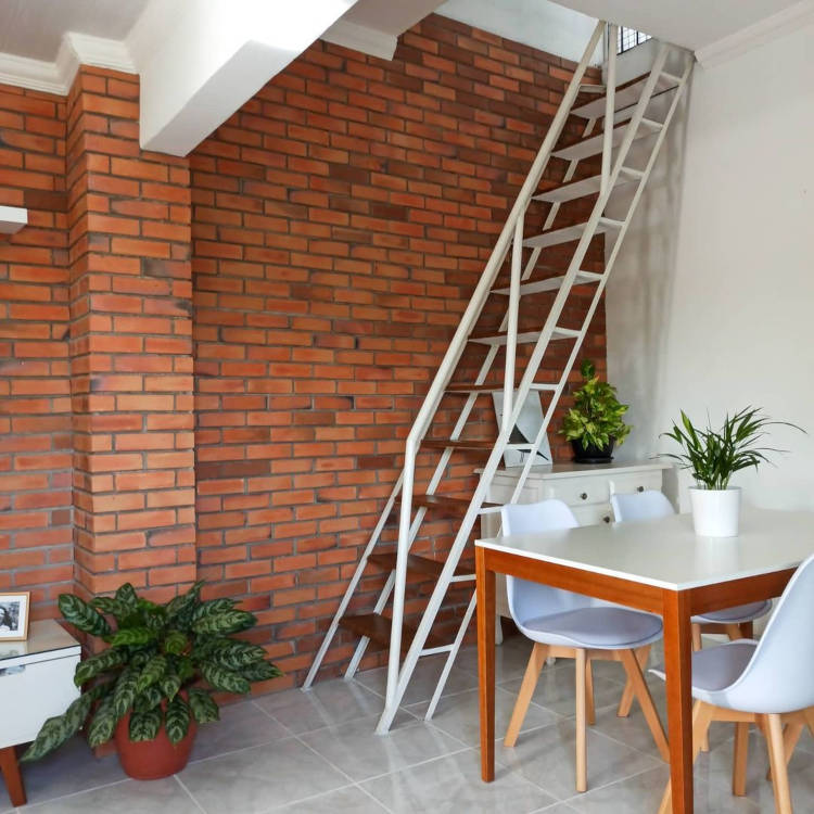 Parede da escada com tijolos à vista.