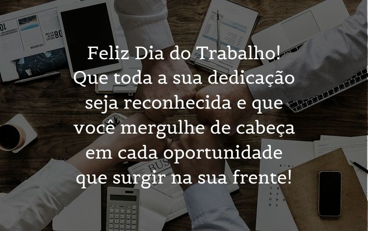 Foto da mão de 4 pessoas sobre mesa bagunçada, com computador, papéis, celulares, tablets e calculadora