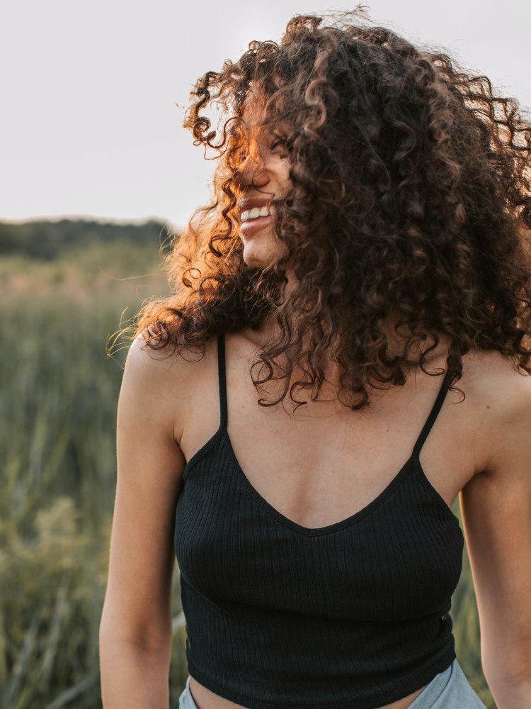 Mulher de cabelos cacheados sorrindo