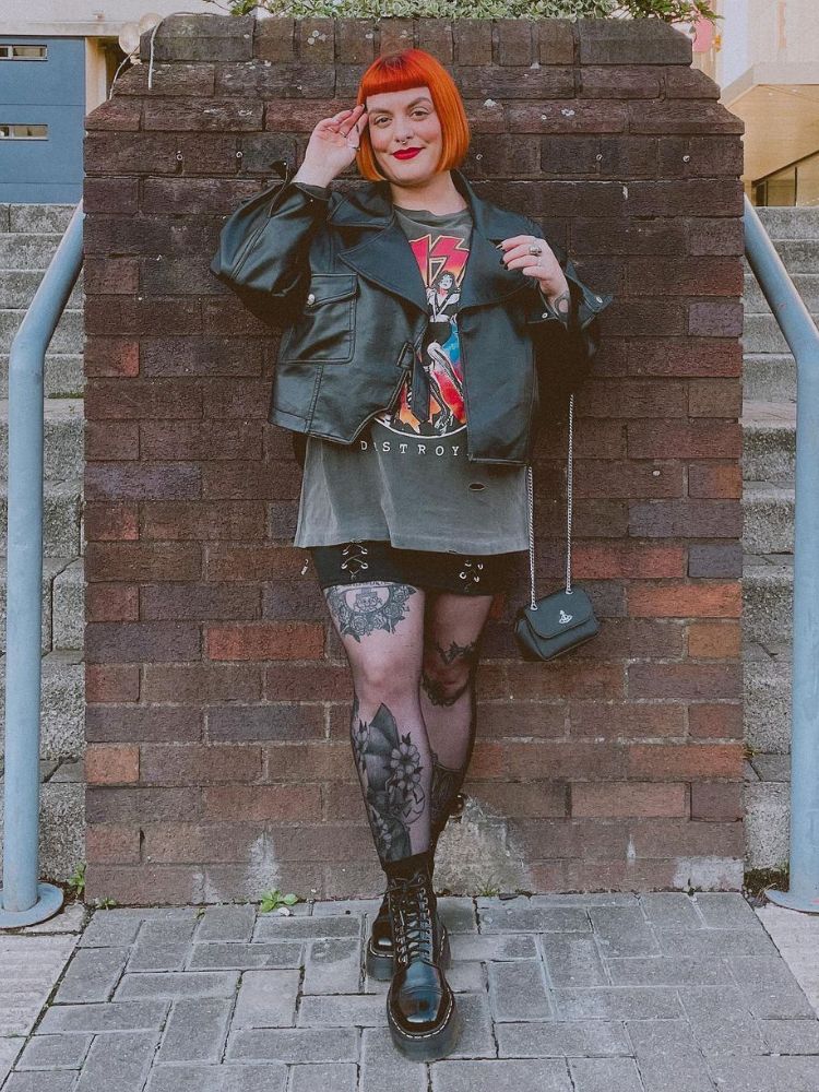 look camiseta de banda com saia preta, meia calça e jaqueta de couro.