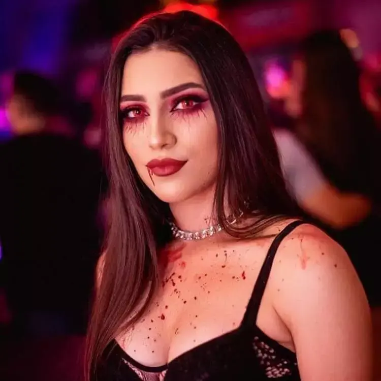 mulher com maquiagem de vampiro, em tons de vermelho e com sangue falso