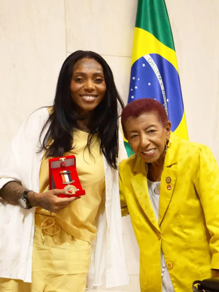 Sára Zarâ de roupa amarela, camisa, ao lado de Leci Brandão