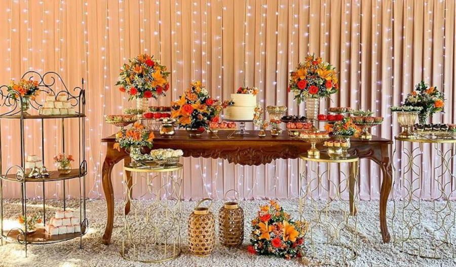 Decoração de casamento simples com flores vermelhas e laranjas e cortina de LED.
