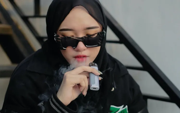 Mulher com óculos de sol fumando vape