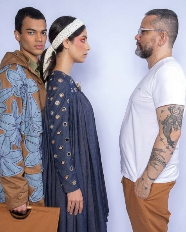 Um casal de modelos posando de perfil encarando o estilista Ronaldo Silvestre