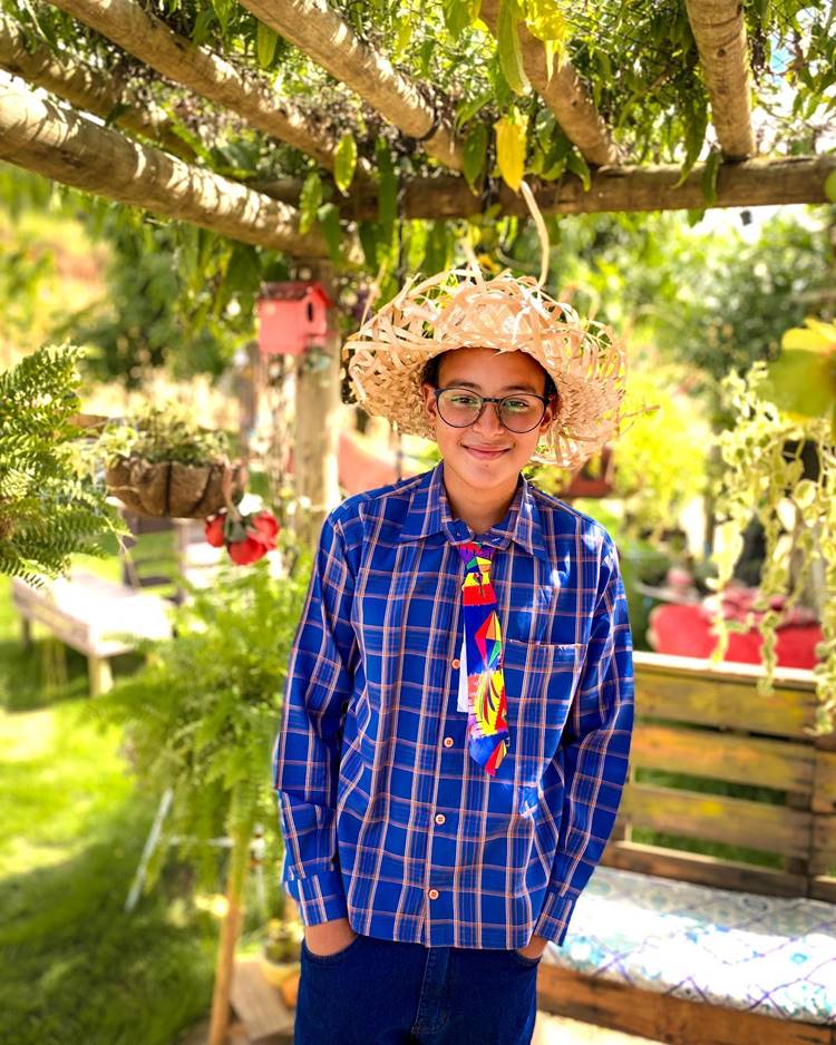 Menino com look de são joão: camisa xadrez azul, chapéu de palha e gravata