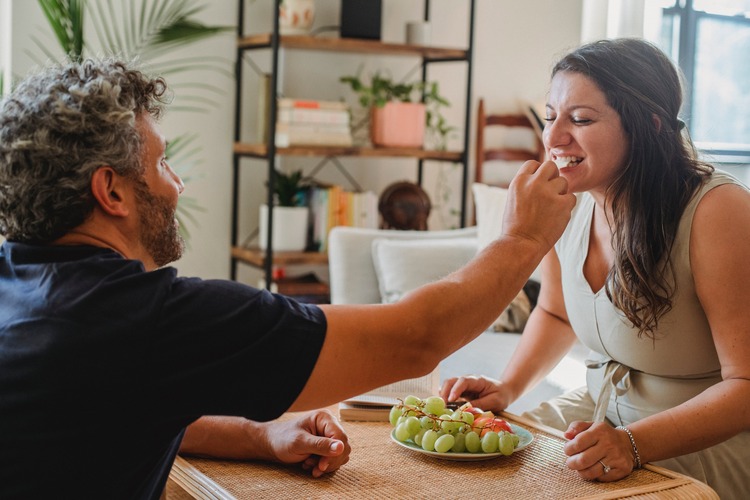 homem dando uvas verdes na boca de uma mulher