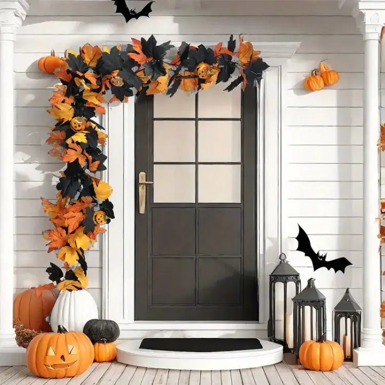 Porta de entrada de casa branca com porta marrom, arco de folhas laranjas, morcego de papel na parede de abóboras no chão 