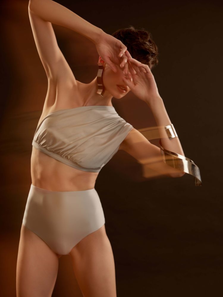 Mulher de pele clara com cropped ombro só e hot pant prateados