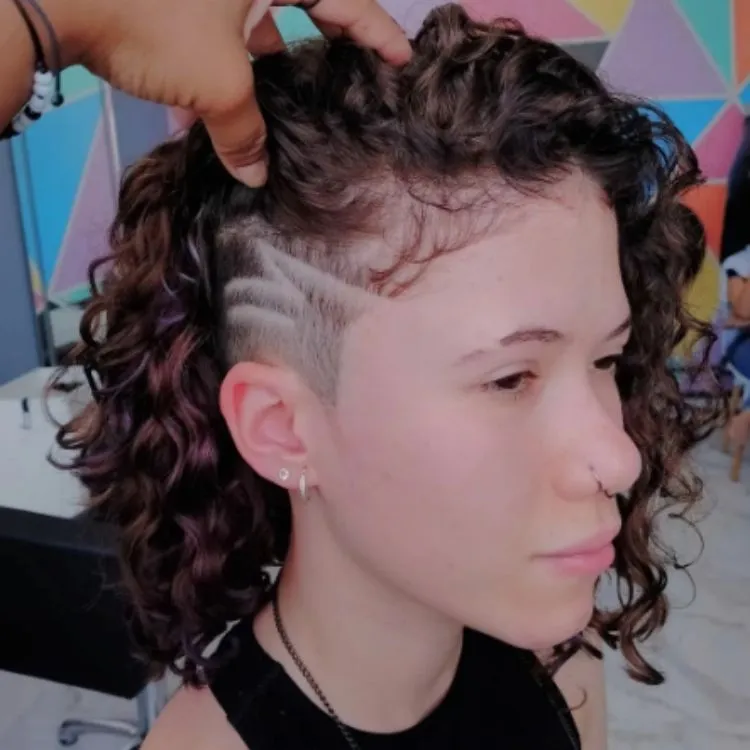 Mulher de pele clara com cabelo cacheado chanel e undercut