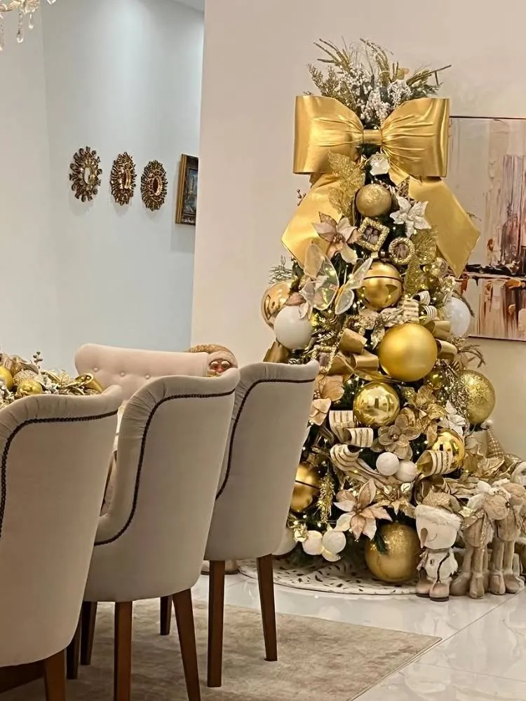 Árvore de Natal verde decorada com laços e bolas douradas gigantes