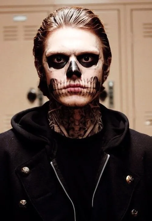 Evan Peters usando maquiagem de caveira, pescoço tatuado e moletom preot 