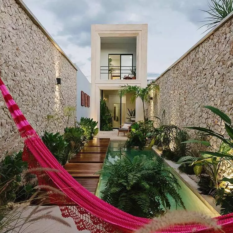Sobrado com sacada e jardim com piscina, caminho de madeira, muitas plantas, rede e parede com detalhes em pedra
