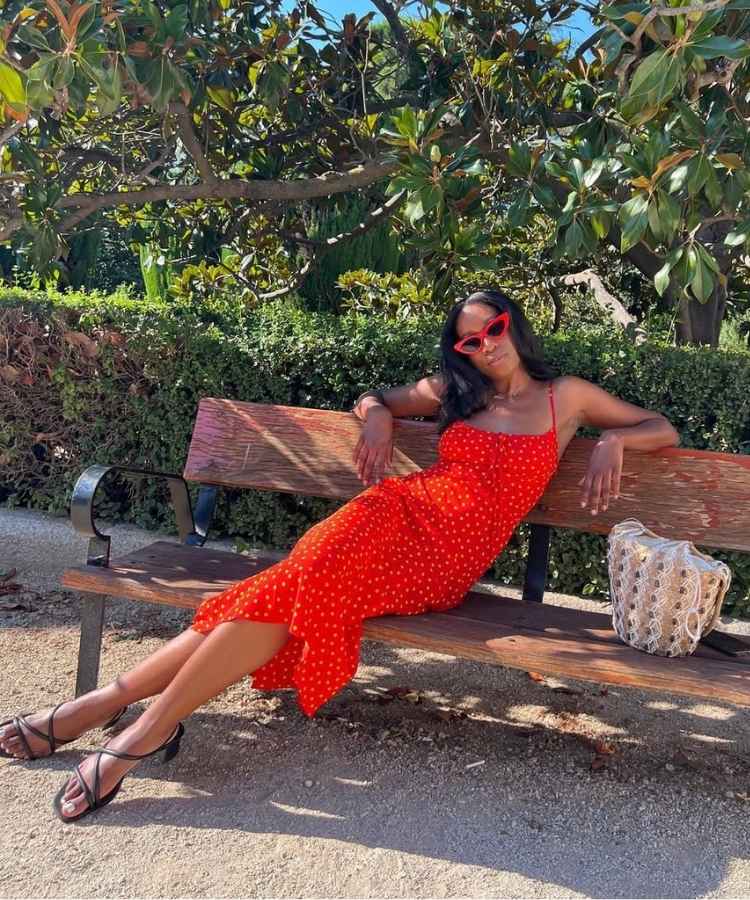 Mulher negra usando vestido vermelho mídi de bolinhas com tamanco preto