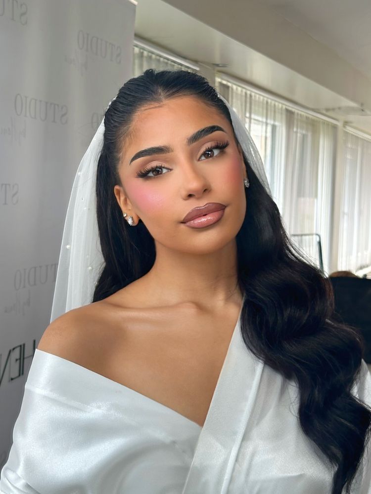 Mulher de pele morena de noiva com boca contornada, maquiagem simples e blush rosado 